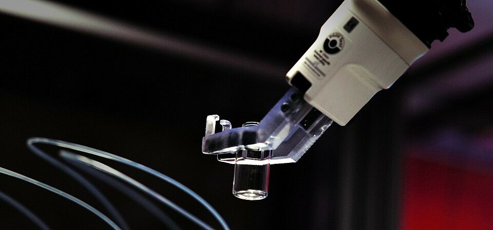 A robotic arm precisely moves an empty sample container back and forth between automated workstations. 